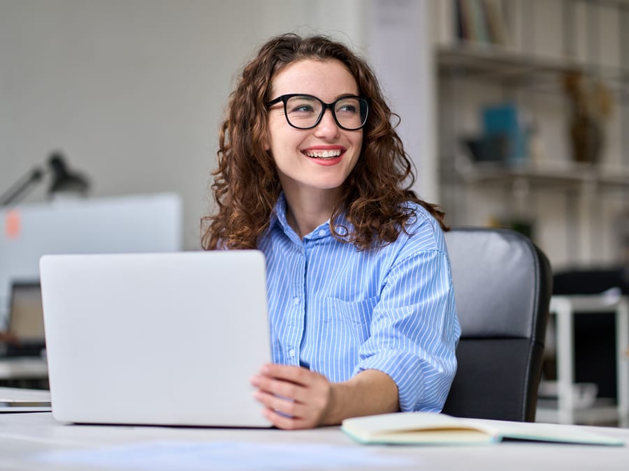 A recent graduate working on her laptop at a bright desk